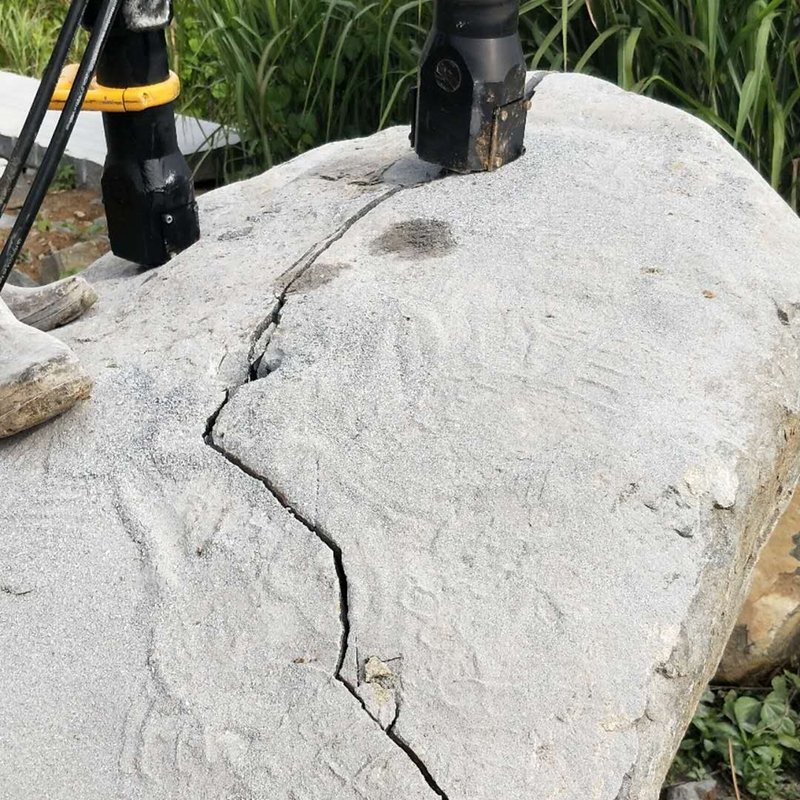 A hydraulic rock splitter breaking a large boulder